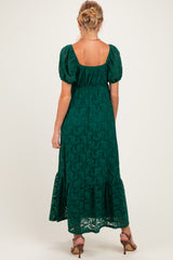 woman wearing a green lace maternity maxi dress with puff sleeves and a tiered hem