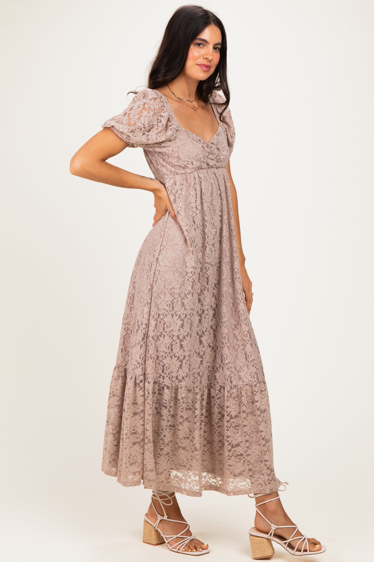woman wearing a beige lace maxi dress with short puff sleeves and a tiered hemline