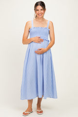 woman wearing a blue and white striped maternity dress with smocked detailing and holding her baby bump
