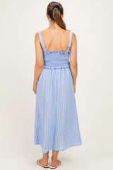 woman wearing a light blue striped maternity dress with a smocked bodice and ruffled detailing