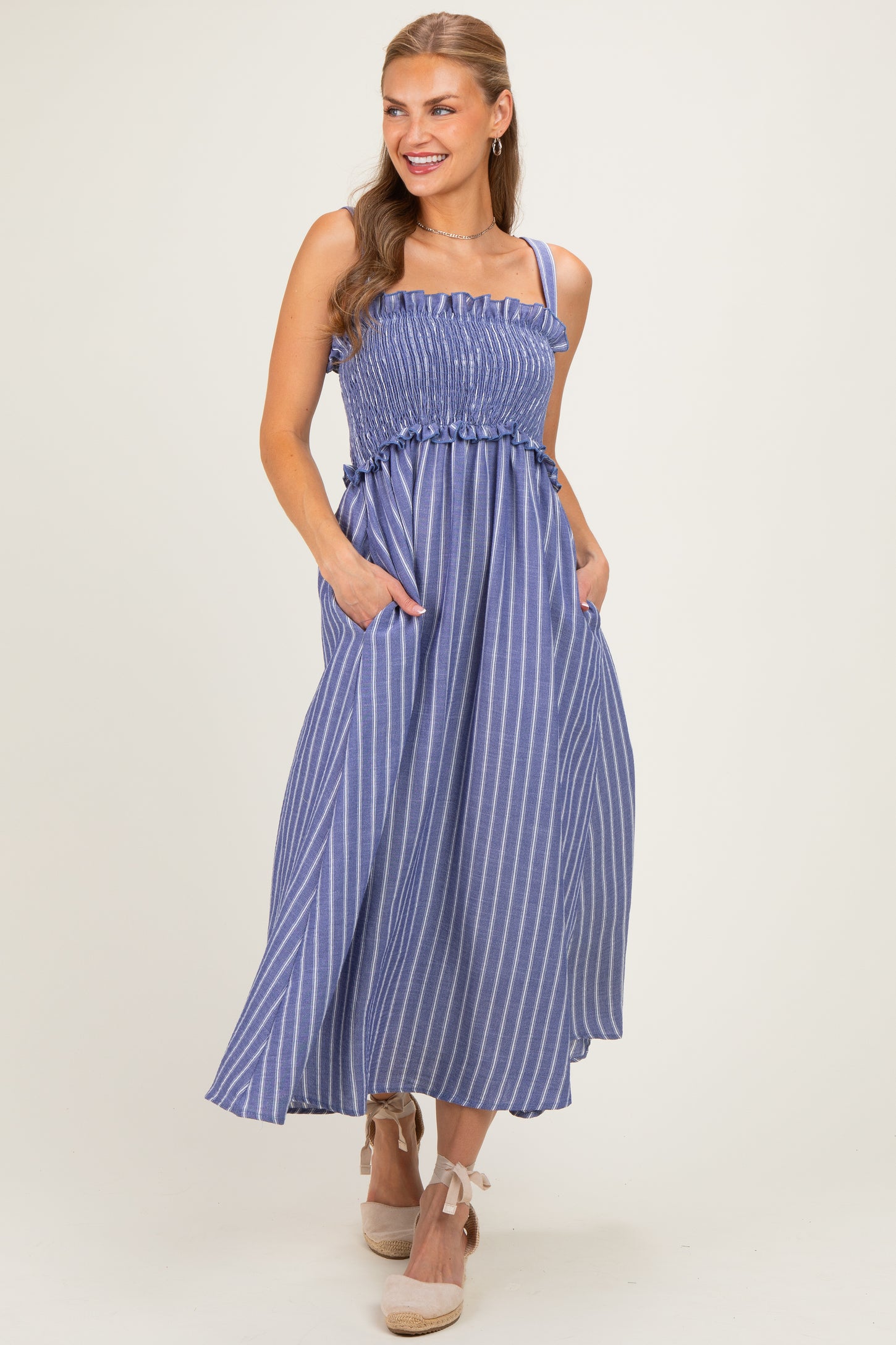 woman wearing a blue and white striped maxi dress with a smocked bodice and pockets, styled with espadrille wedges