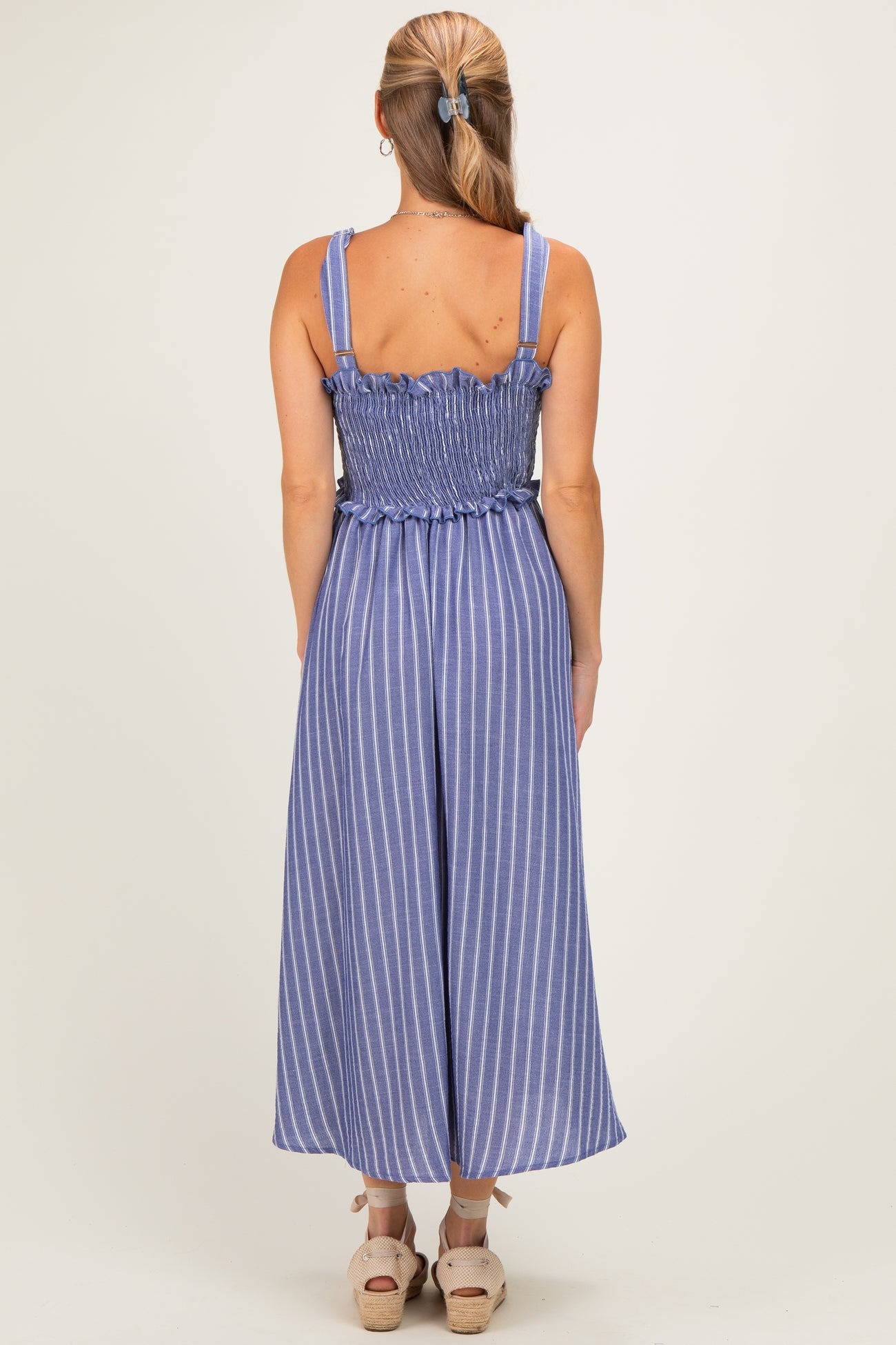 woman wearing a blue and white striped backless jumpsuit with smocked waist and wide legs