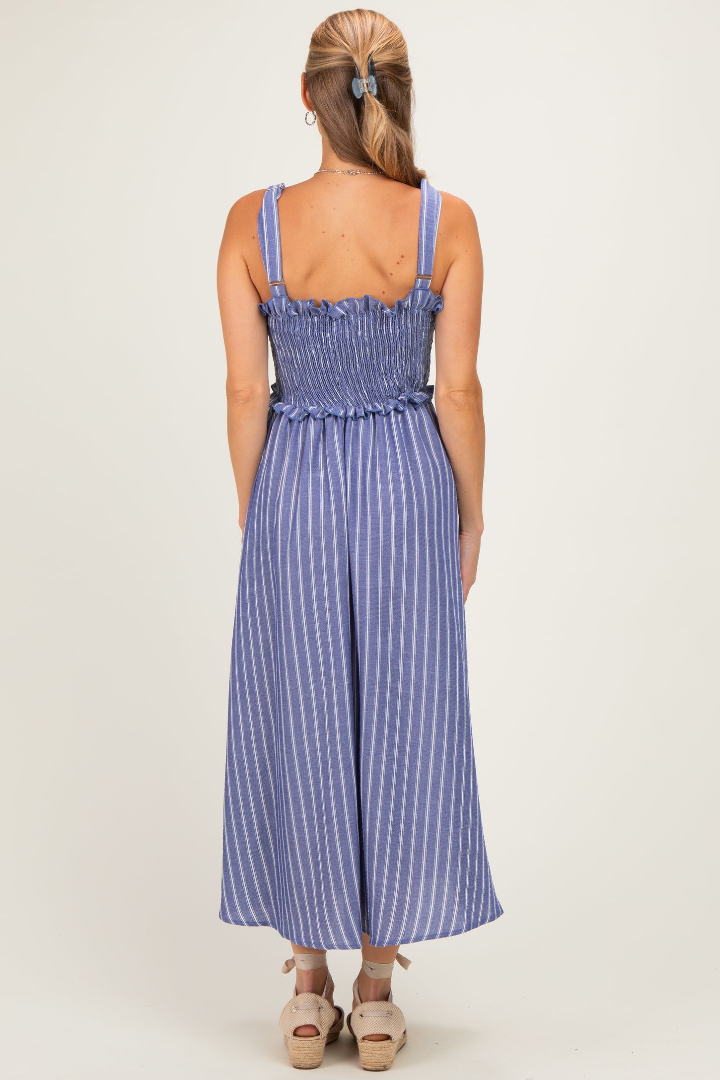 woman wearing a blue and white striped backless jumpsuit with smocked waist and wide legs
