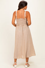 woman wearing a beige striped maternity dress with smocked bodice and adjustable straps, showing her baby bump from the back