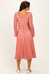 woman wearing a pink maternity dress with long sleeves and a flared skirt, showing the back view