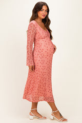 woman wearing a pink floral maternity dress with long sleeves and a visible baby bump