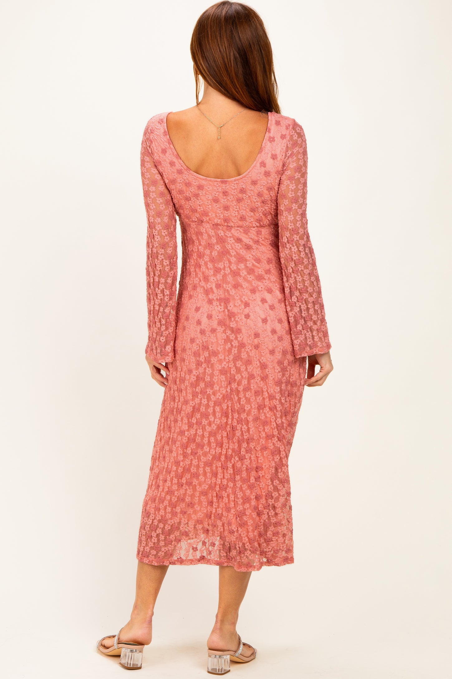 woman wearing a pink long sleeve midi dress with a floral pattern and a scoop back view