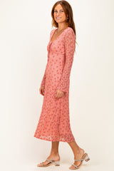 woman wearing a pink floral long sleeve midi dress with a v-neck and flared sleeves