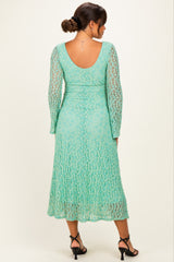 woman wearing a mint green lace maternity dress with long sleeves and a flowing skirt, viewed from the back