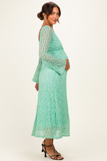 woman wearing a mint green lace maternity dress with flared sleeves and holding her baby bump