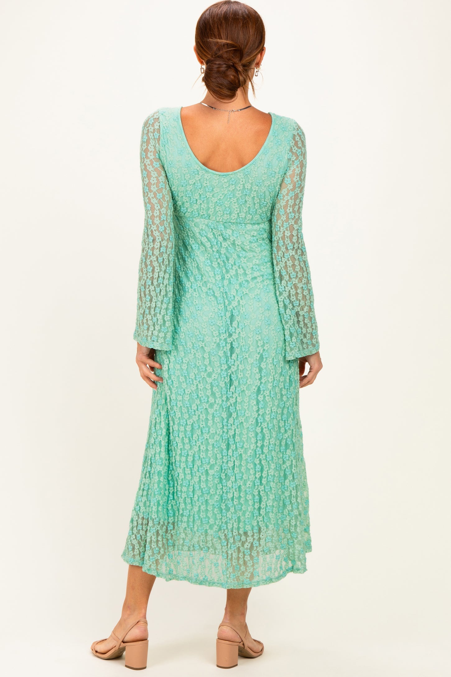 woman wearing a mint green long sleeve lace dress with a flowing skirt and a scoop back