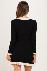 woman wearing a black ribbed maternity dress with cream ruffle details on the sleeves and hem