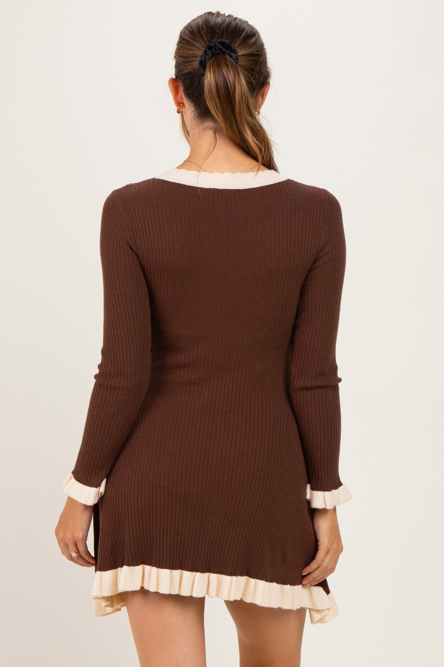 woman wearing a brown ribbed maternity dress with ruffled hem and sleeves, showing a relaxed fit and back view