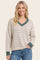 woman wearing a cream and green striped v-neck sweater with a relaxed fit and long sleeves