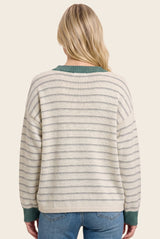woman wearing a cream and gray striped oversized sweater with a green collar, showing the back view