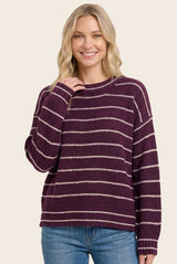 woman wearing a burgundy and cream striped oversized sweater with a relaxed fit and long sleeves