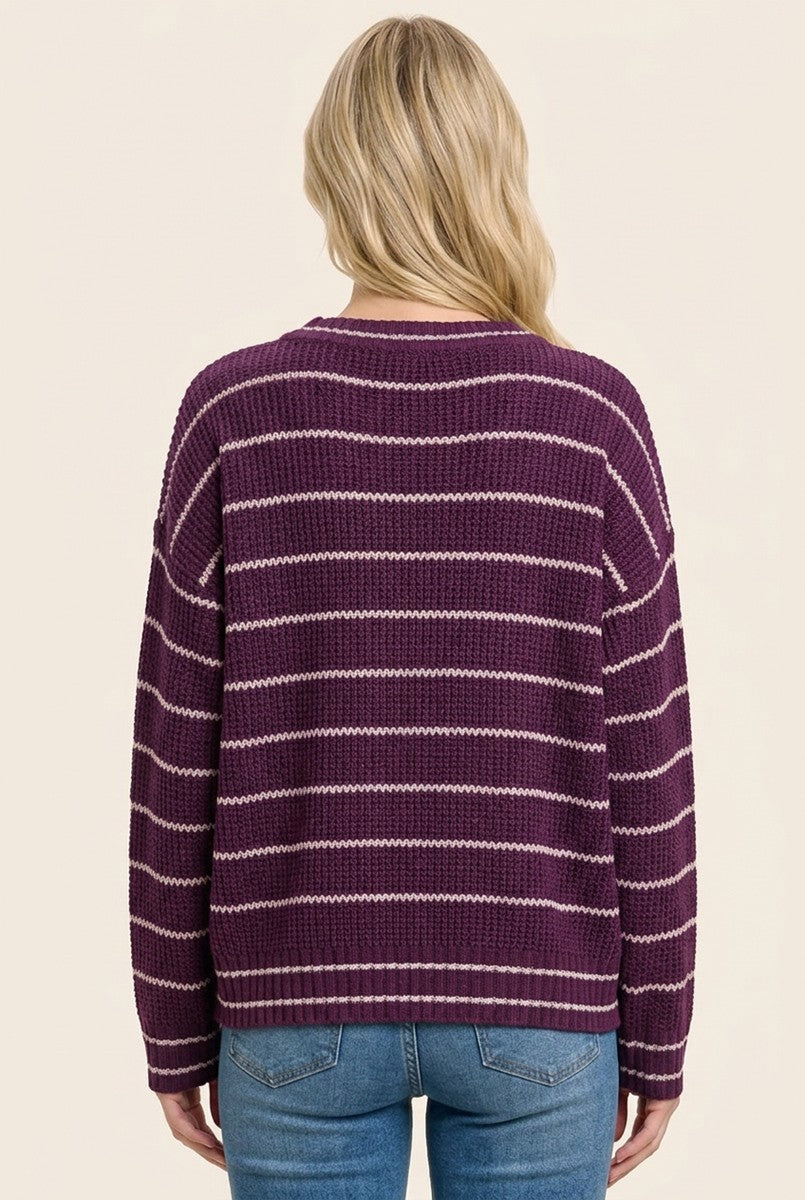 woman wearing a purple striped knit sweater and blue jeans, viewed from the back