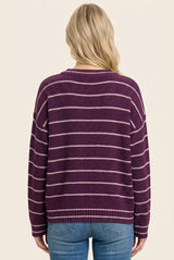 woman wearing a purple striped knit sweater and blue jeans, viewed from the back