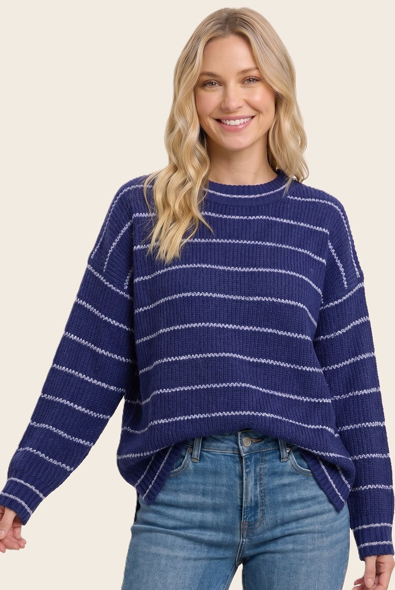 woman wearing a navy blue striped sweater with a relaxed fit and long sleeves, paired with light denim jeans