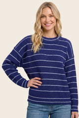 woman wearing a navy blue striped sweater with white accents and relaxed fit, paired with light blue jeans