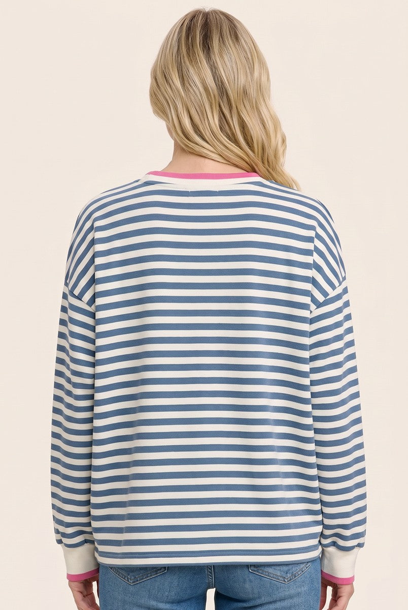 woman wearing a blue and white striped long sleeve sweatshirt with pink neckline, seen from the back