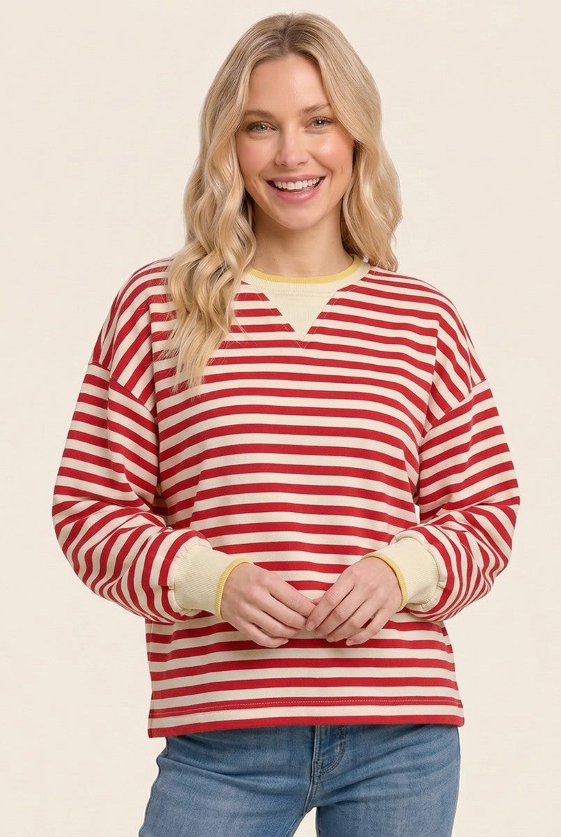 woman wearing a red and white striped long sleeve pullover with yellow trim and blue jeans