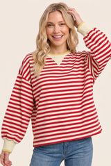 woman wearing a red and cream striped oversized sweatshirt with balloon sleeves and a v-neckline