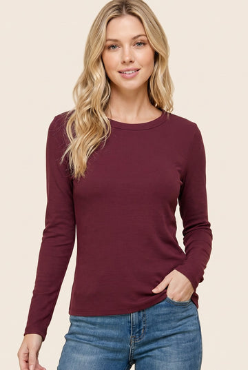 woman wearing a burgundy long sleeve ribbed top and blue jeans