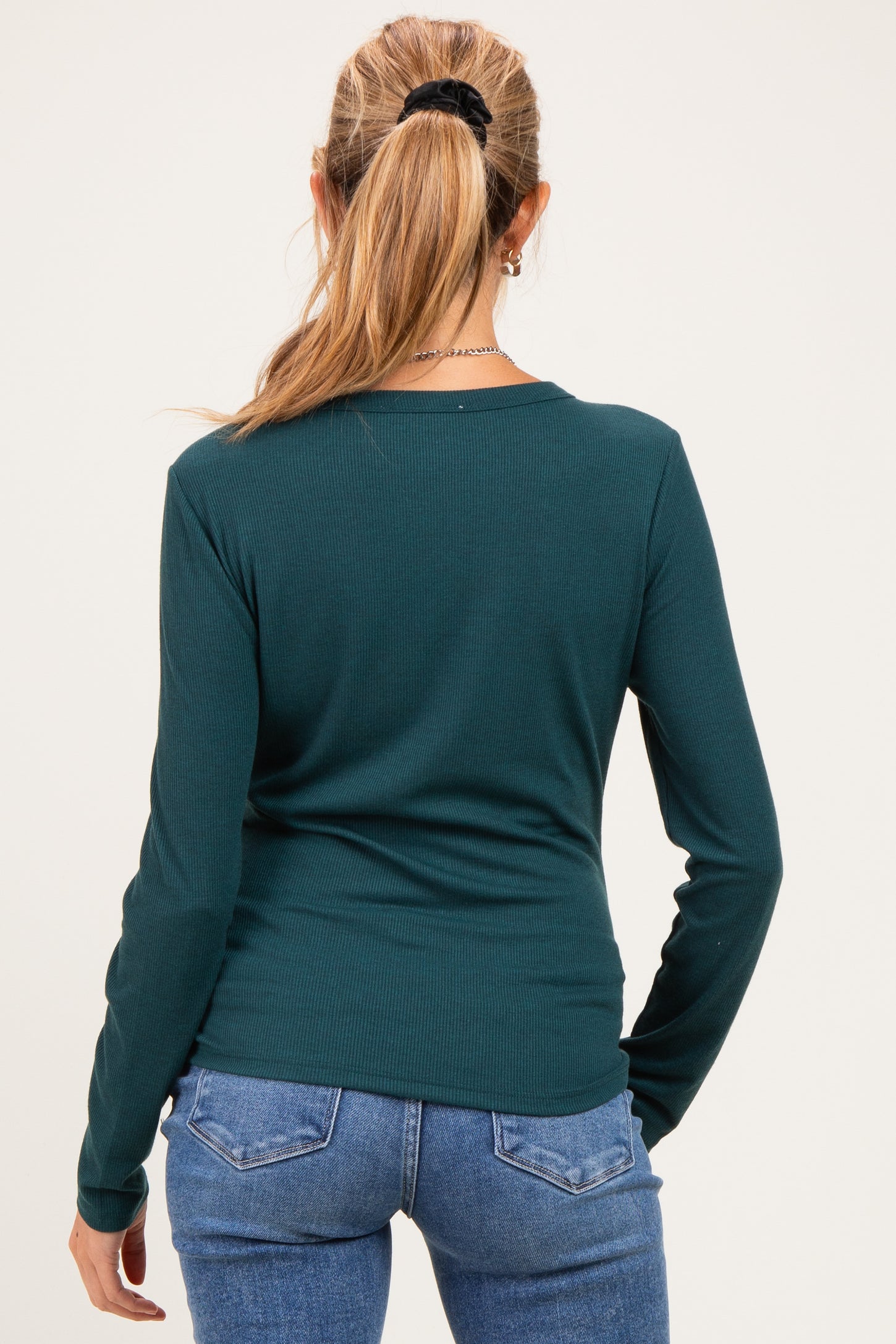 woman wearing a dark green long sleeve maternity top viewed from the back with fitted design and casual style