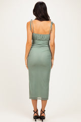 woman wearing a muted green midi dress with adjustable straps and a fitted silhouette