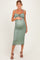 woman wearing a sage green maternity dress with tie straps and a fitted silhouette, showcasing her baby bump