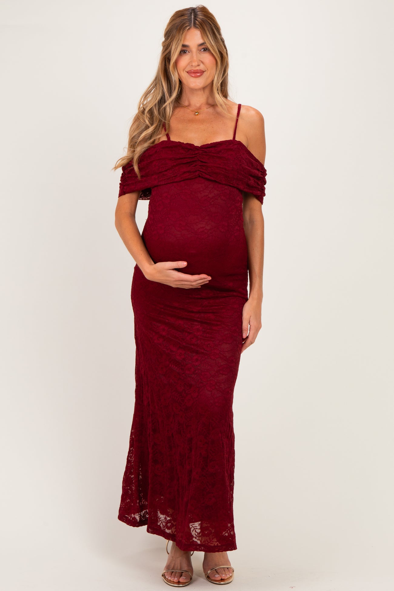 woman wearing a burgundy lace off-the-shoulder maternity dress showing her baby bump