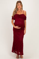 woman wearing a burgundy lace off-the-shoulder maternity dress showing her baby bump