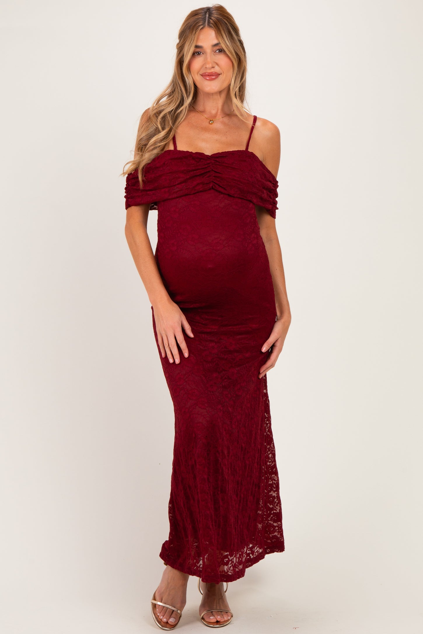 woman wearing a burgundy lace off-the-shoulder maternity dress with a fitted silhouette and a visible baby bump