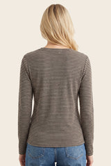 woman wearing a brown and white striped long sleeve top, viewed from the back, paired with blue jeans