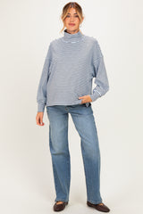 woman wearing a blue and white striped maternity sweater with a high neck and relaxed fit, paired with light jeans