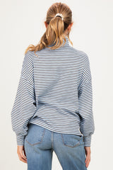 woman wearing a light blue striped maternity sweater with a relaxed fit and balloon sleeves, seen from the back