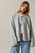 woman wearing a light gray button-up cardigan layered over a white top and paired with high-waisted jeans