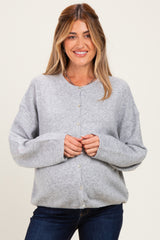 woman wearing a gray maternity cardigan with button closure and relaxed fit, smiling while holding her baby bump