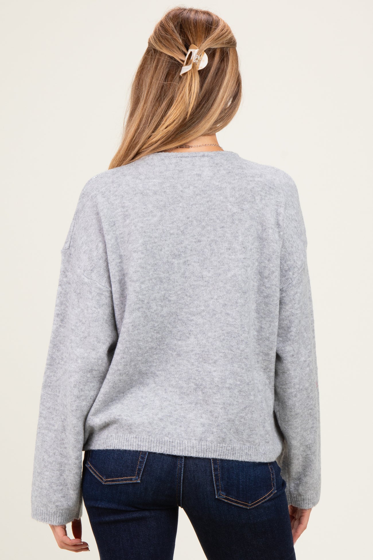 woman wearing a light gray maternity sweater with a relaxed fit and long sleeves, viewed from the back