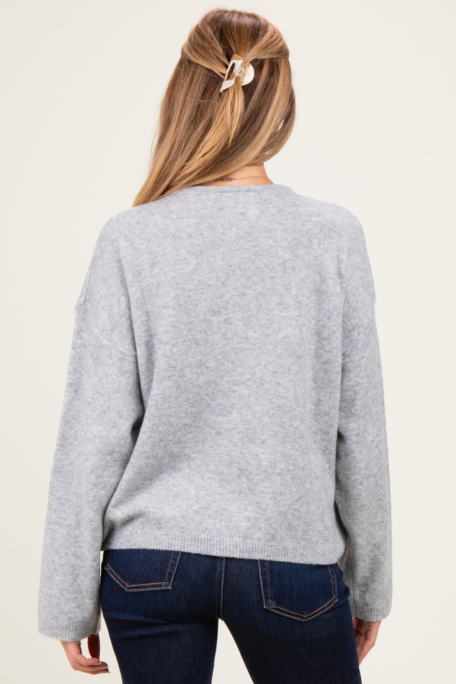woman wearing a light gray maternity sweater with a relaxed fit and long sleeves, viewed from the back