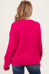 woman wearing a hot pink oversized maternity sweater, view from the back, styled with blue jeans