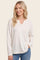 woman wearing a light cream long sleeve ribbed top with a v-neckline and relaxed fit, smiling and posing casually