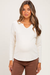 woman wearing a white long sleeve maternity top with a v-neck and visible baby bump