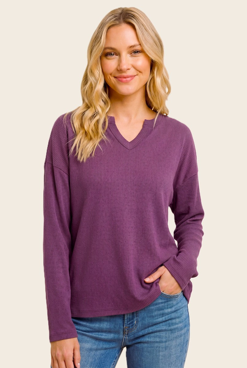 woman wearing a purple long sleeve waffle knit top with a v-neck and relaxed fit, styled with blue jeans