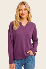 woman wearing a purple long sleeve waffle knit top with a v-neck and relaxed fit, styled with blue jeans