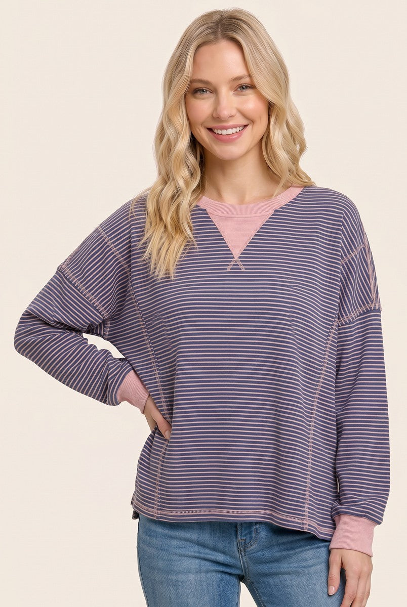 woman wearing a striped oversized pullover sweatshirt in purple and pink with a relaxed fit and long sleeves