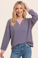woman wearing a purple and pink striped long sleeve sweatshirt and smiling