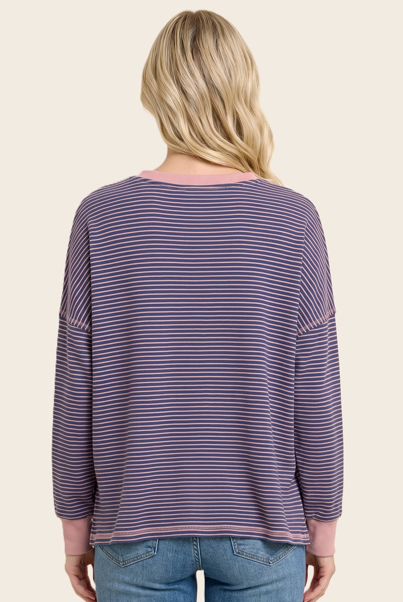 woman wearing a striped purple and pink oversized long sleeve top, shown from the back