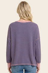 woman wearing a striped purple and pink oversized long sleeve top, shown from the back